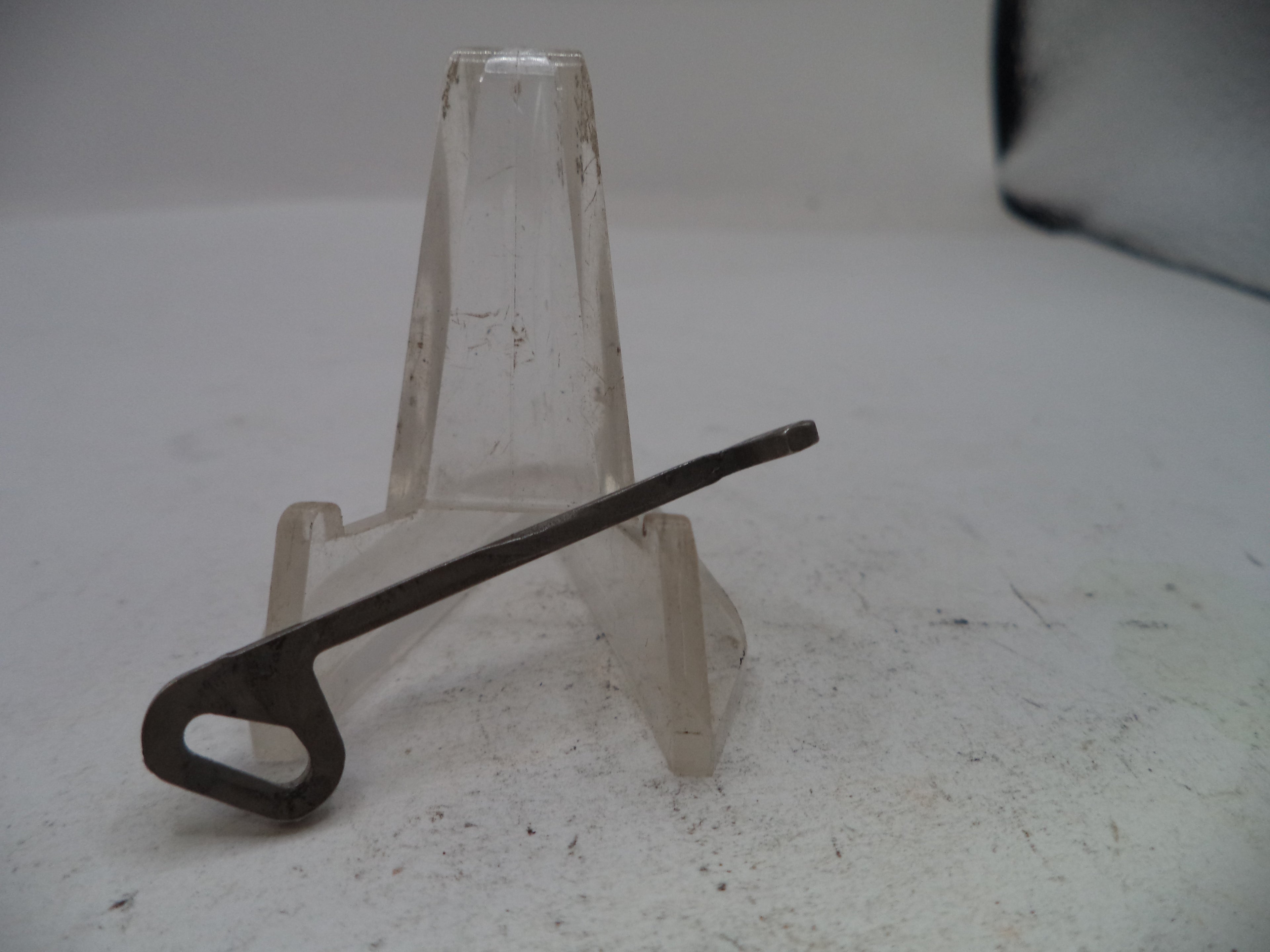 Metal key on a clear plastic stand against a plain background