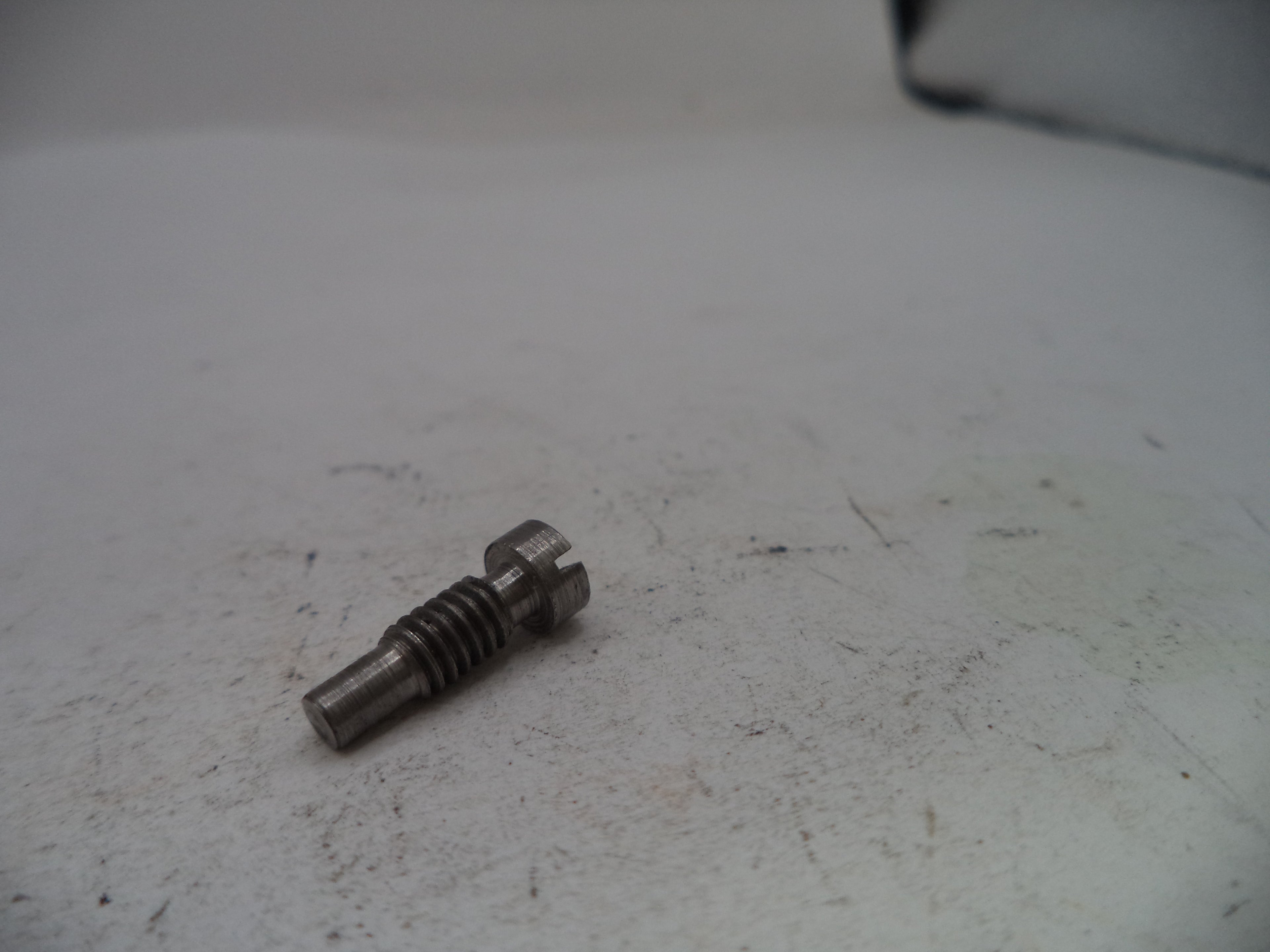 Metal screw on a worn white surface