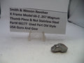 Small metal thumb piece and nut on a white surface with descriptive text card.