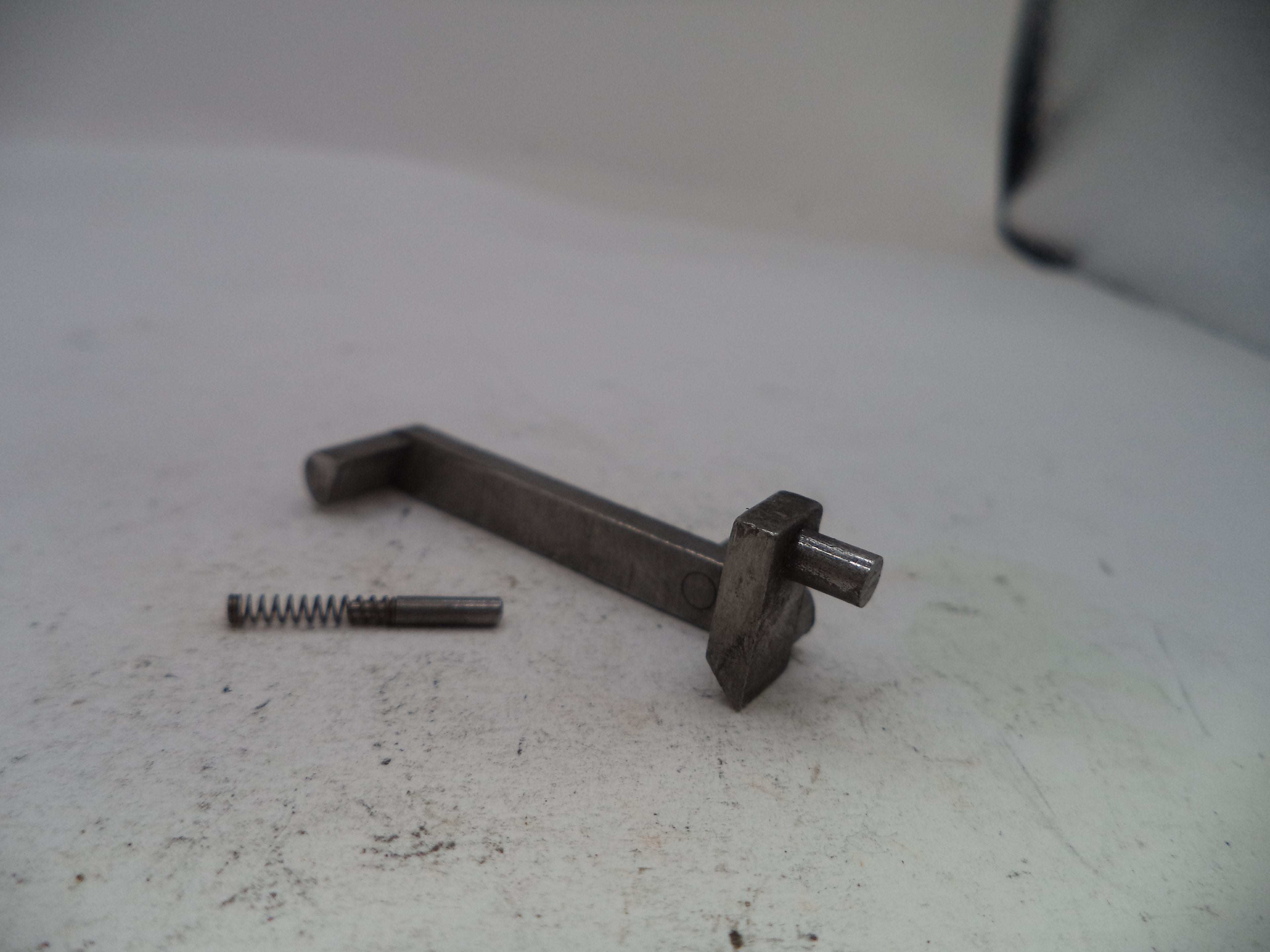 Metal lever and spring on a textured white surface