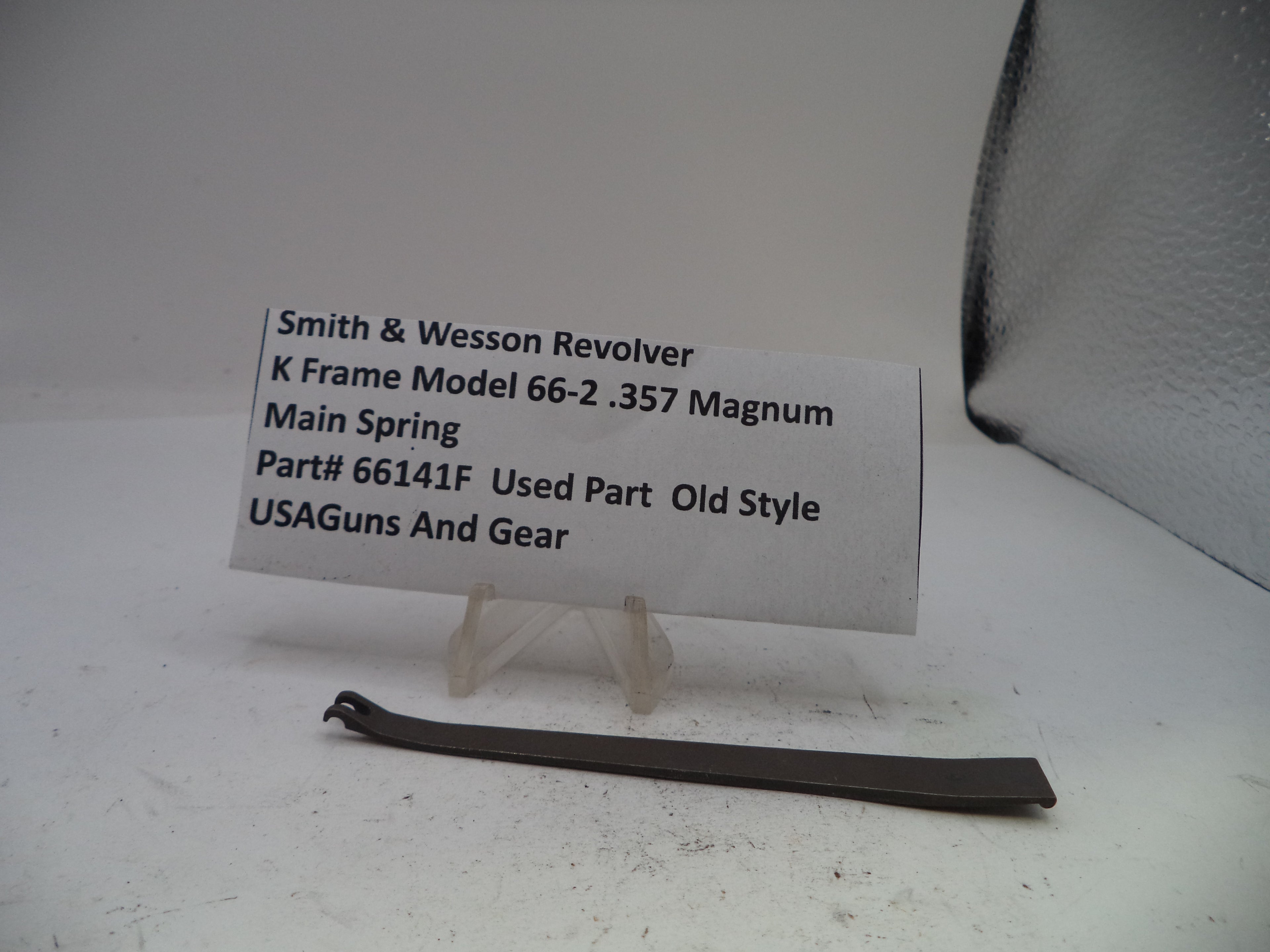 Smith & Wesson revolver main spring with a label on a white background