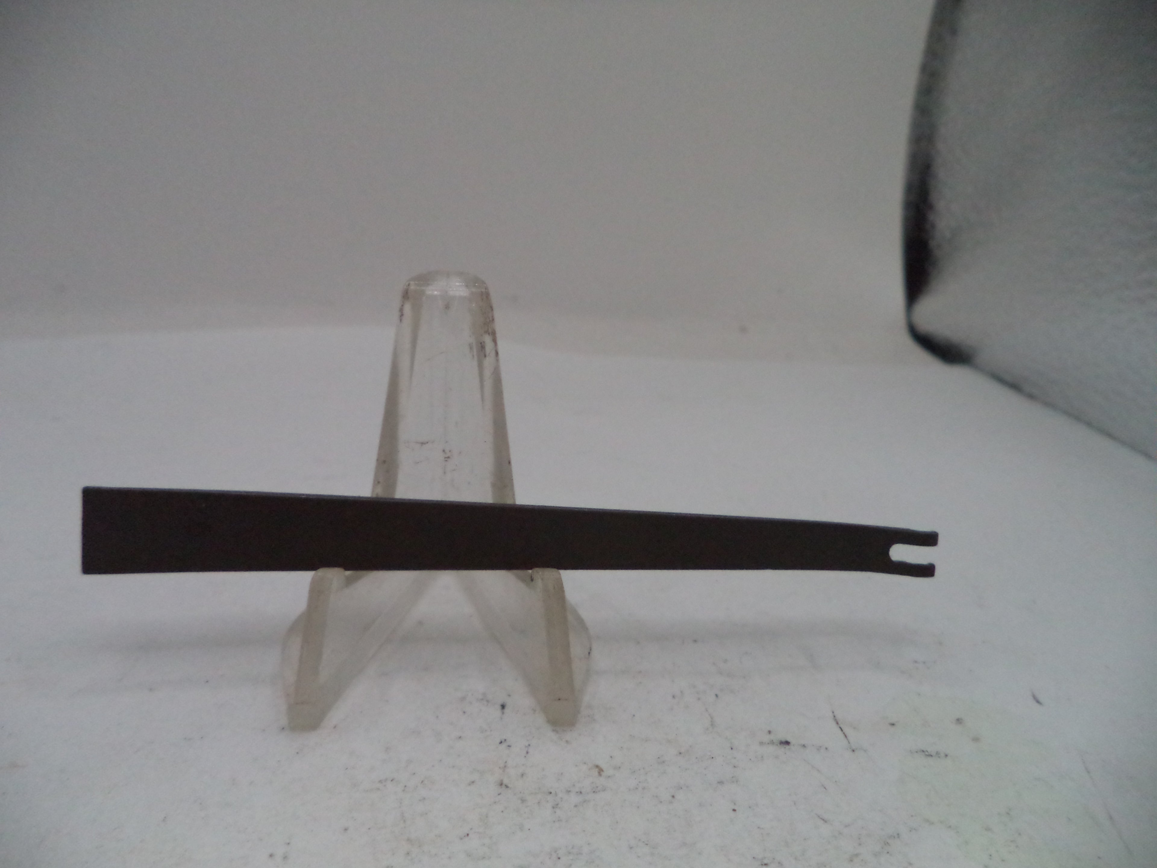 Black metal blade on a clear stand against a white background