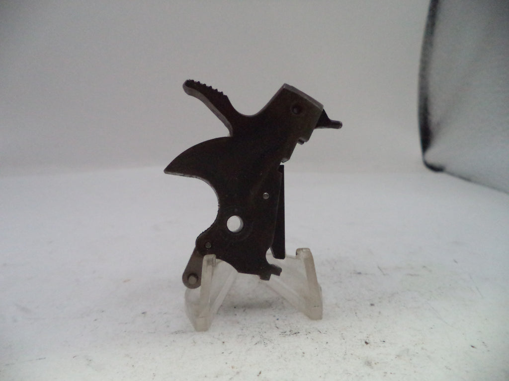 A small dark metal mechanical part or tool component displayed upright on a clear plastic stand against a plain light background.