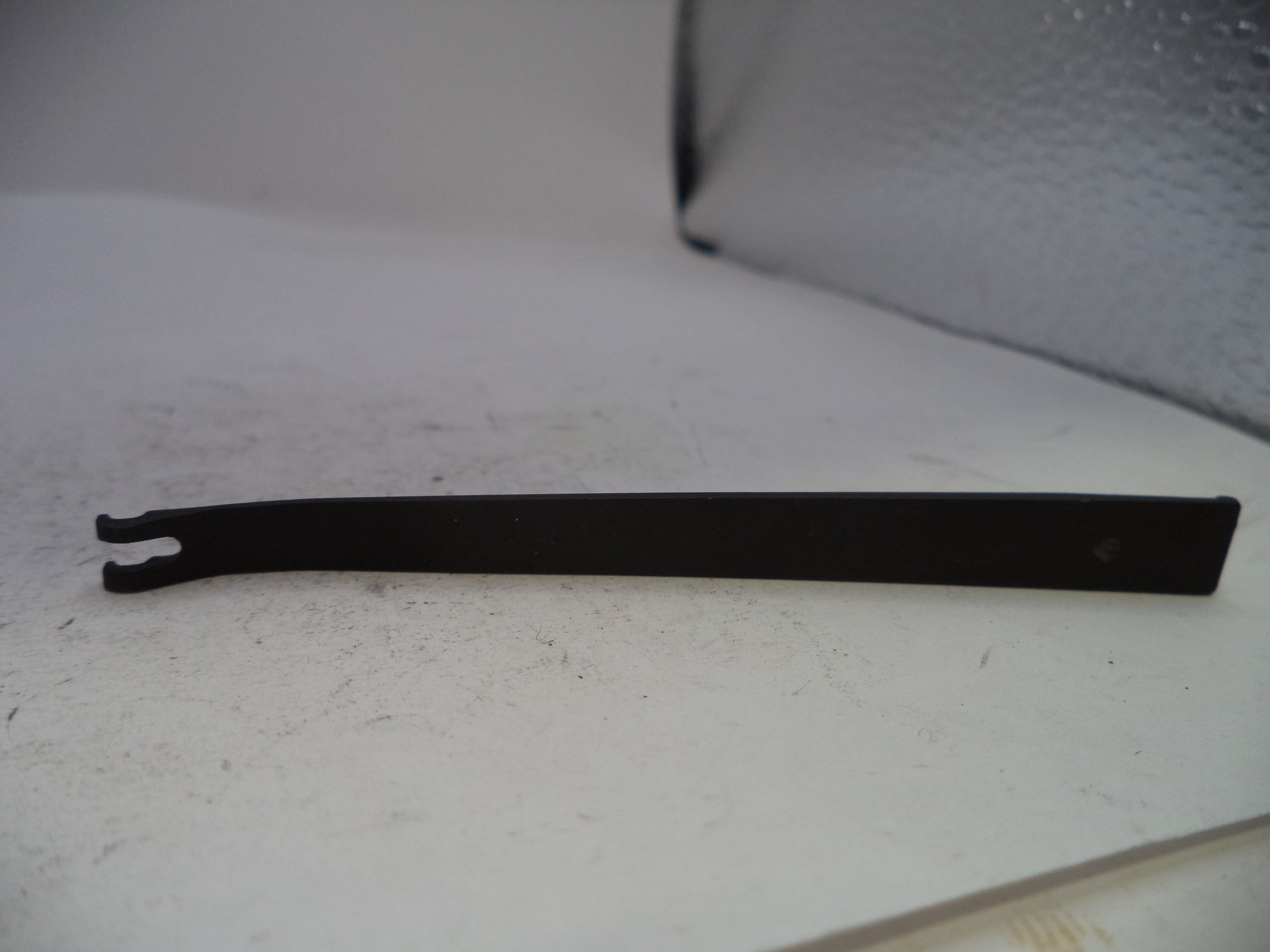 A black metal flathead screwdriver or pry tool with a forked tip, resting on a white surface.