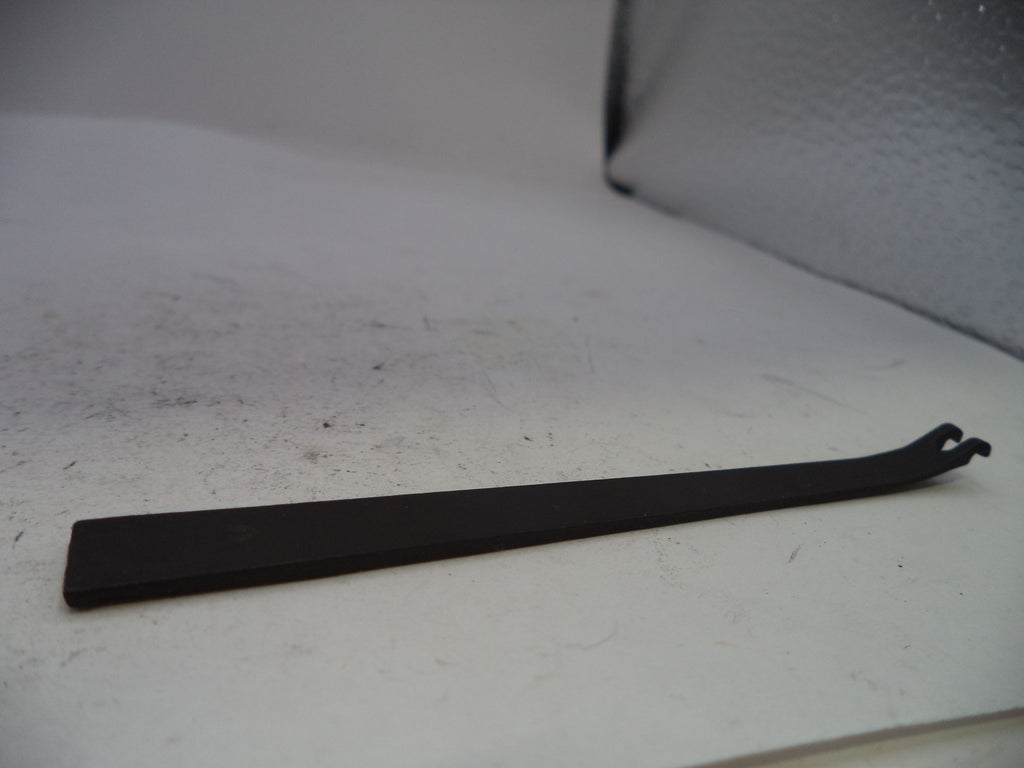 A long, flat black metal tool with a bent hook-like end, photographed on a light gray surface.