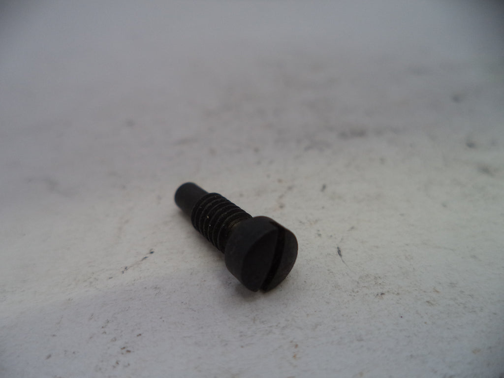 A small black metal screw with a slotted hex head, lying on a light gray textured surface.