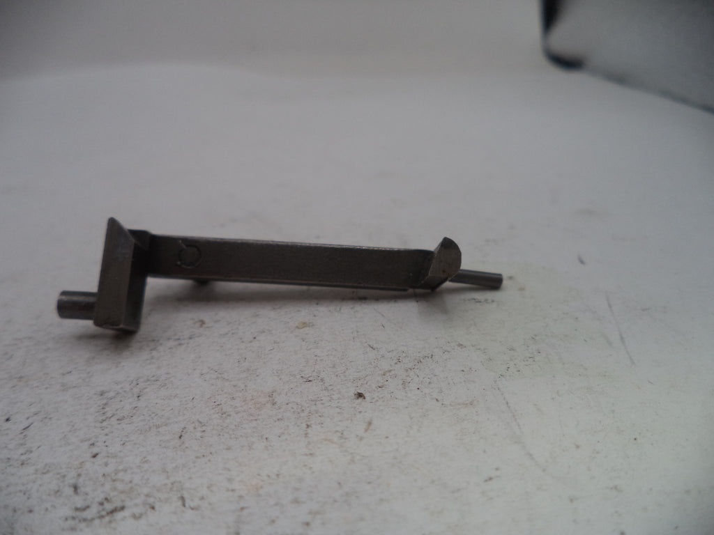 A small dark metal hardware piece, possibly a bracket or latch component, lying on a light gray textured surface.
