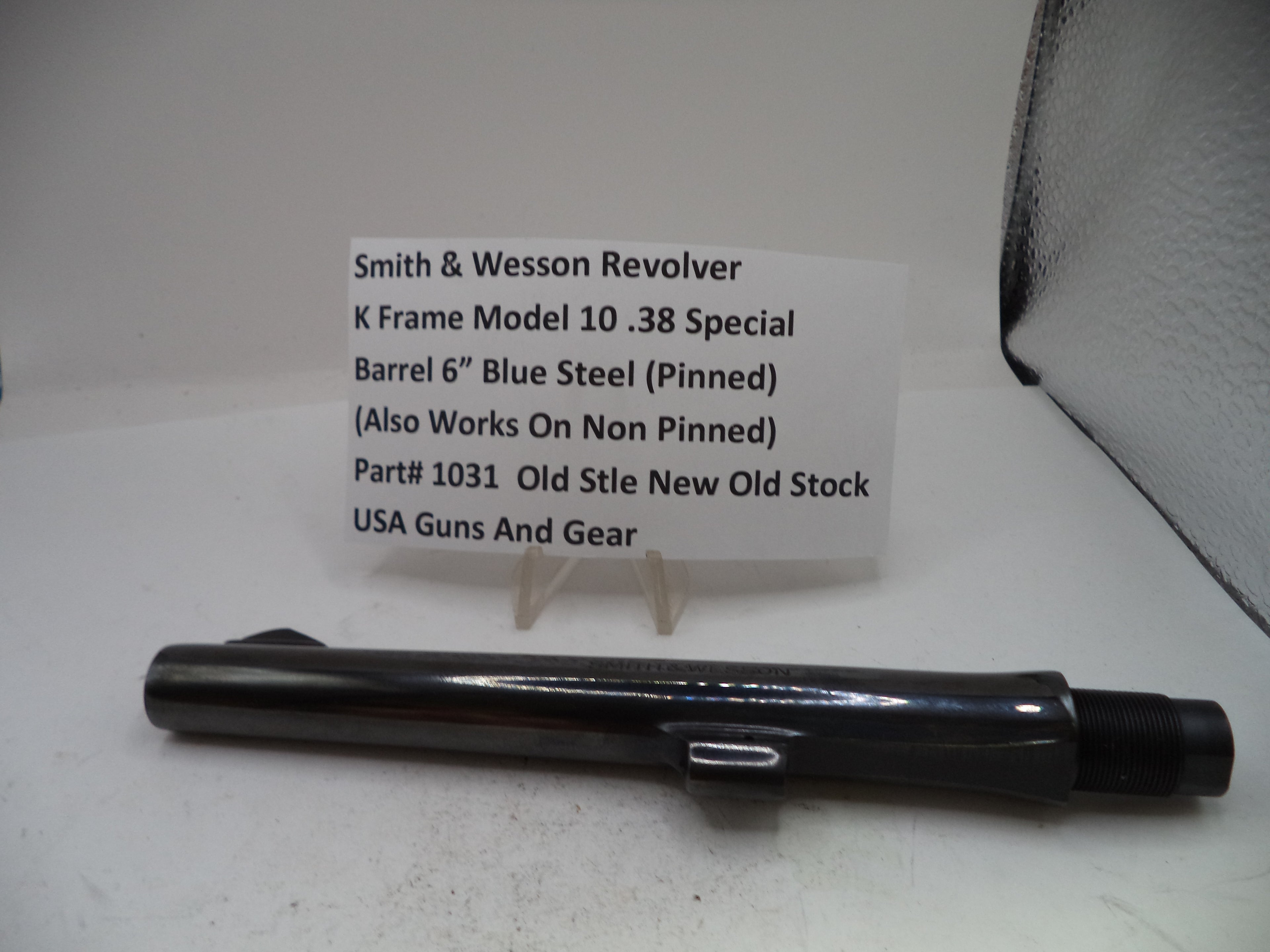 A black Smith & Wesson revolver K frame barrel replacement part displayed on a white surface with a white product information card in front.