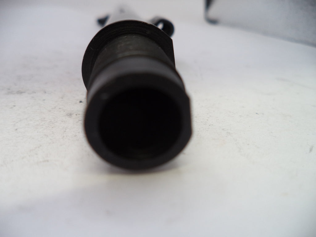 A close-up shot of a black cylindrical plastic or rubber component, possibly a nozzle or connector, resting on a white surface.