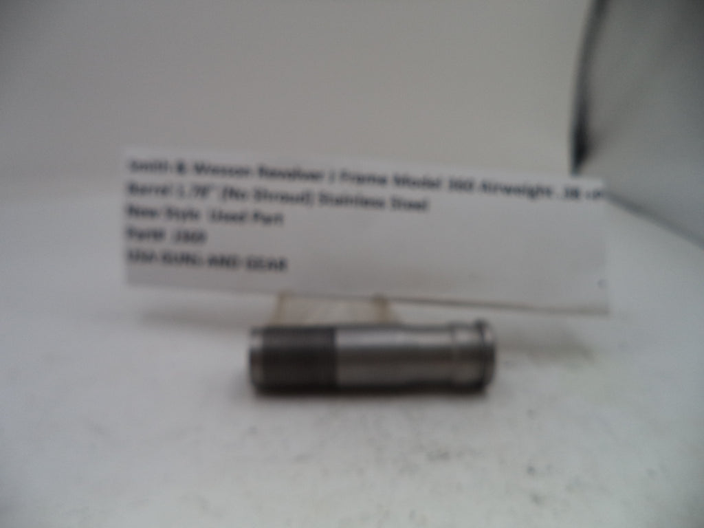 A small cylindrical metal part with a white label card behind it on a light surface. The label appears to read Smith & Wesson Basilore 1 Frame Model 500 Airstream .