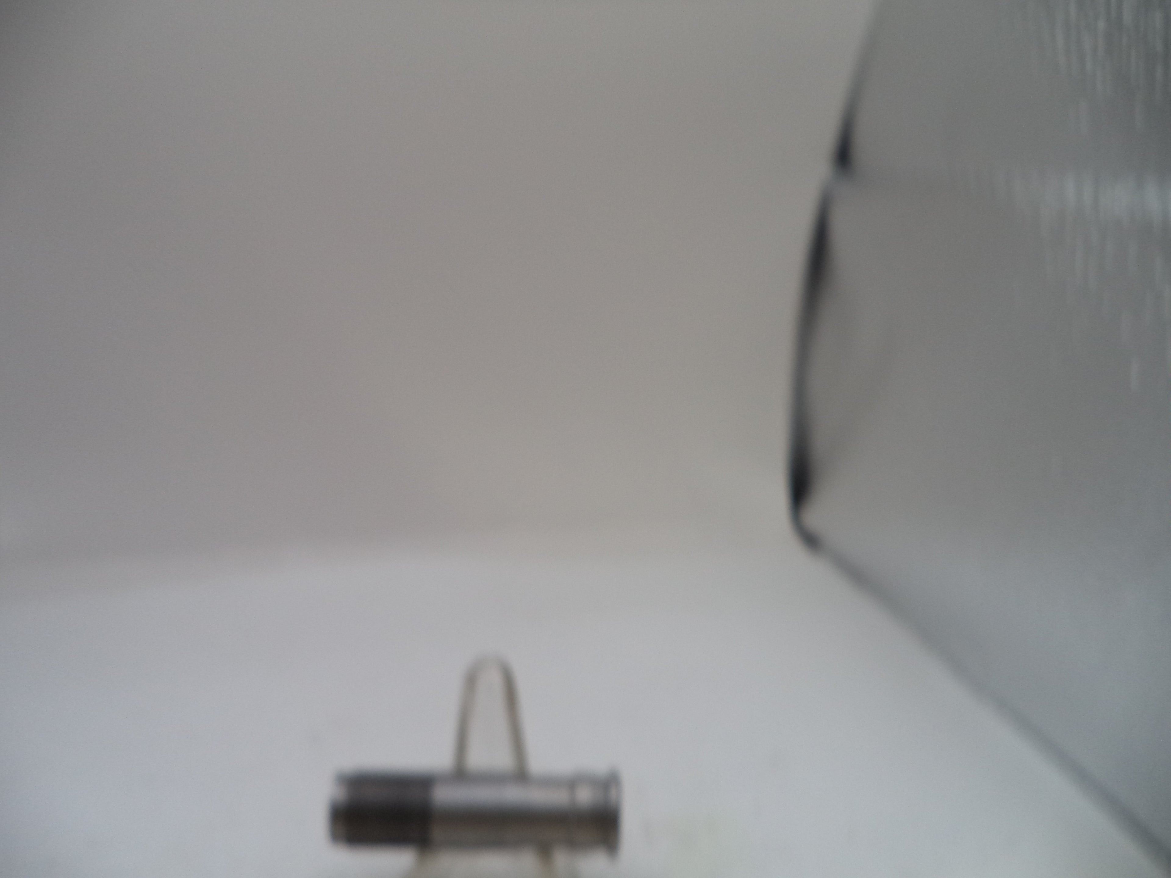 A small cylindrical metal hardware component, possibly a bolt or pin, displayed on a small stand against a plain light background.