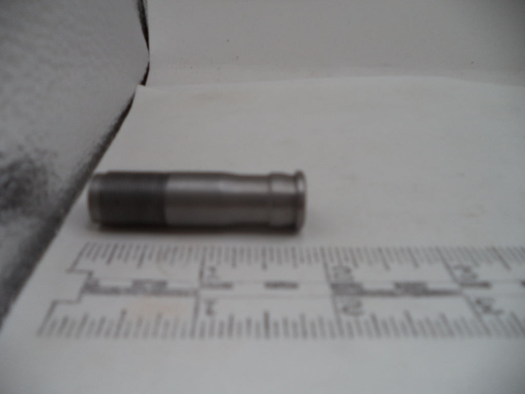 A small metallic cylindrical object, possibly a bullet casing or prop, resting on a white surface with a ruler in the foreground for scale.