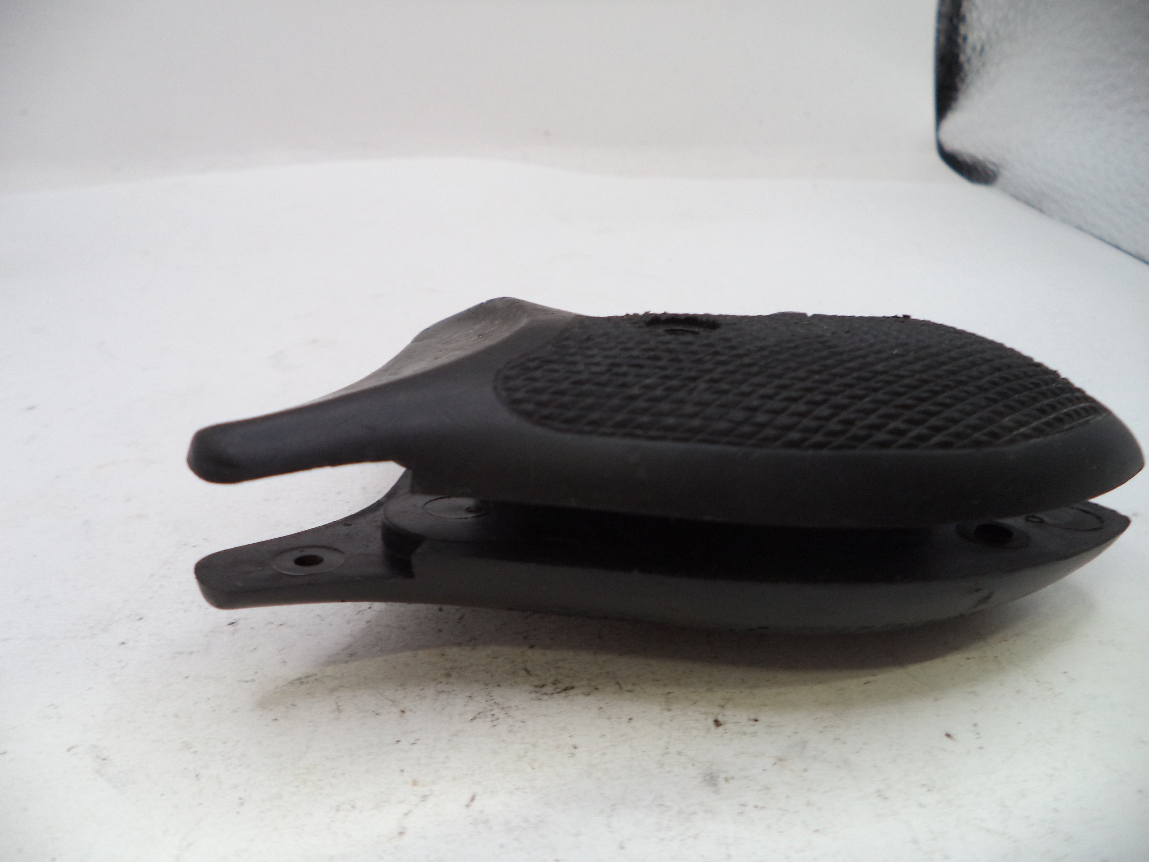 A black textured rubber or polymer accessory piece, possibly a grip or protective cover, shown on a white surface.