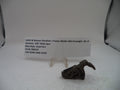 A used metal hammer component for a Smith & Wesson revolver, displayed on a small clear stand next to a white paper label card on a white surface.