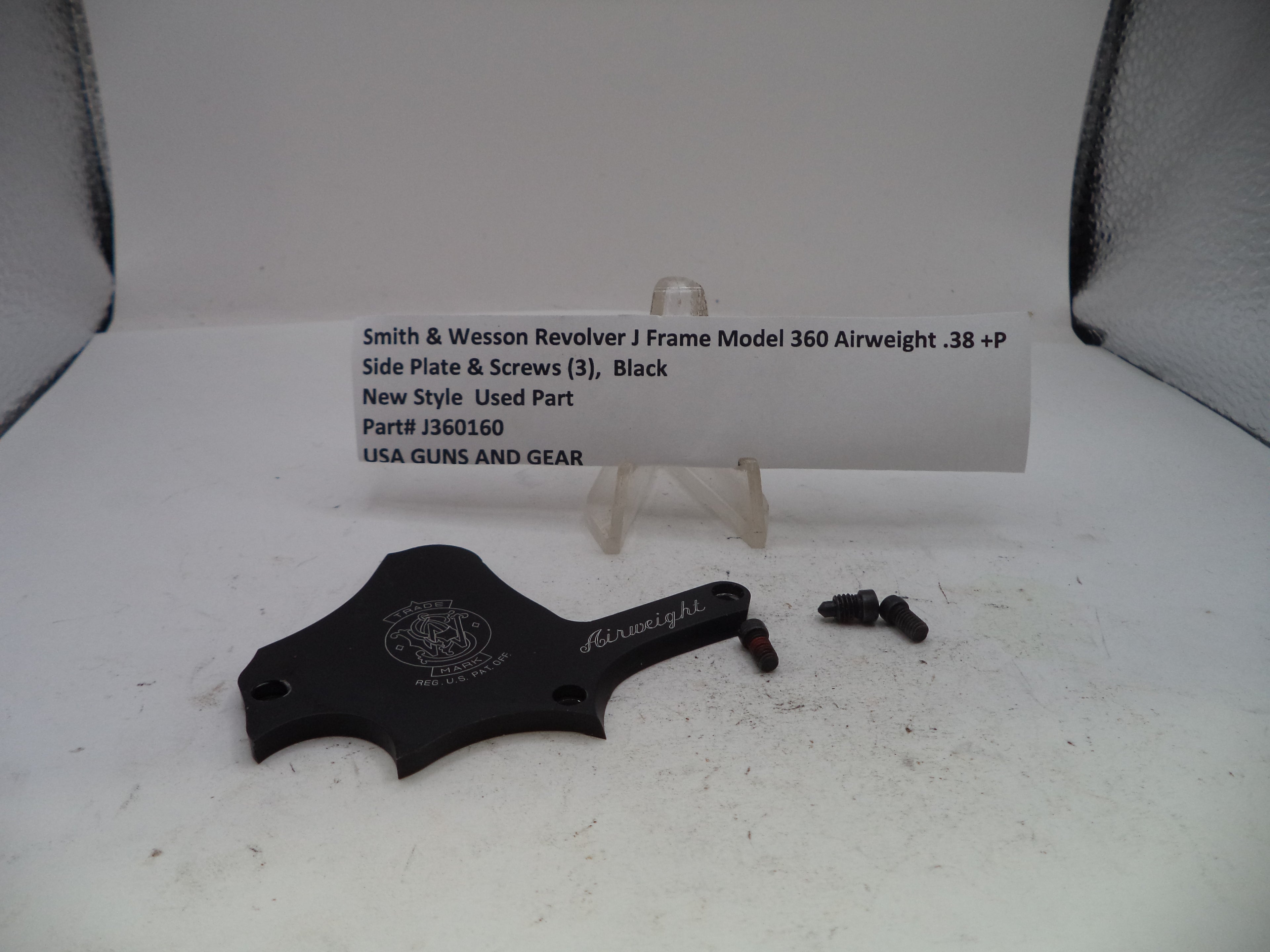 A black metal side plate and screws for a Smith & Wesson revolver airweight, displayed on a white surface with a product information card behind it.