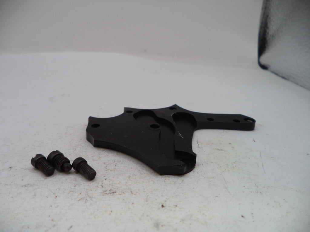 A black plastic or metal mounting bracket with three small dark screws, photographed on a white surface with a white backdrop.