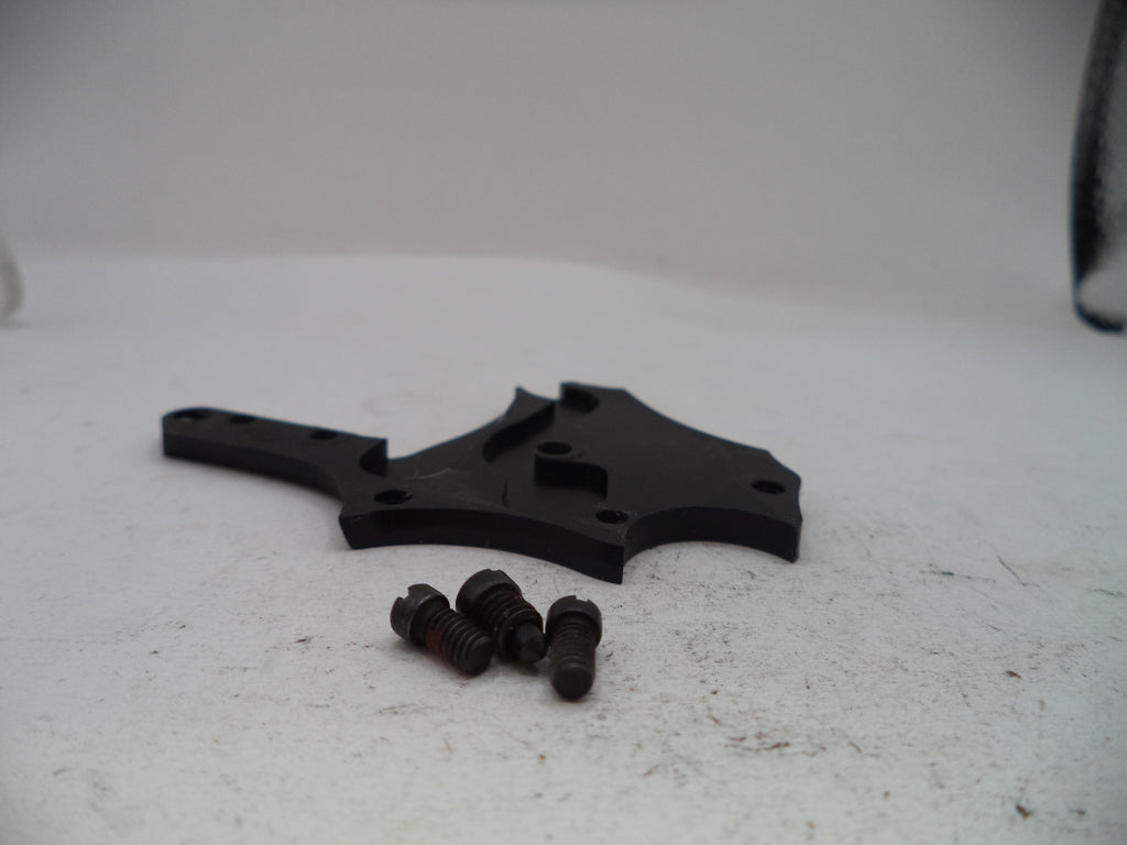 A black plastic mounting bracket with three small black screws, photographed on a light gray surface.