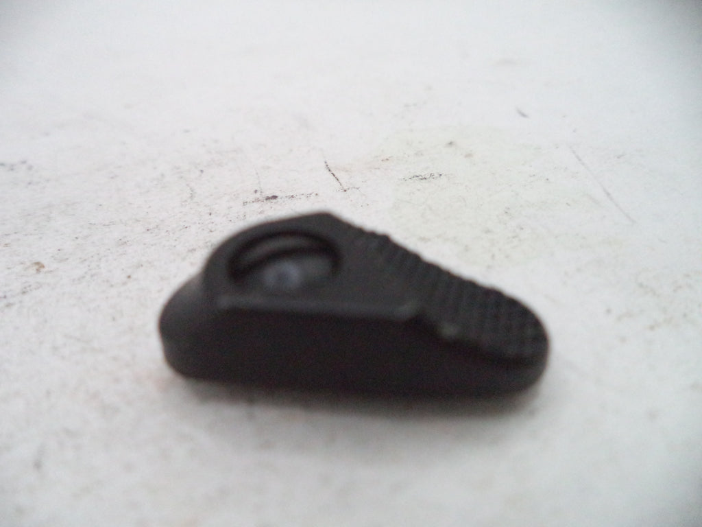 A small black textured plastic component with a circular recess, photographed on a light off-white surface.