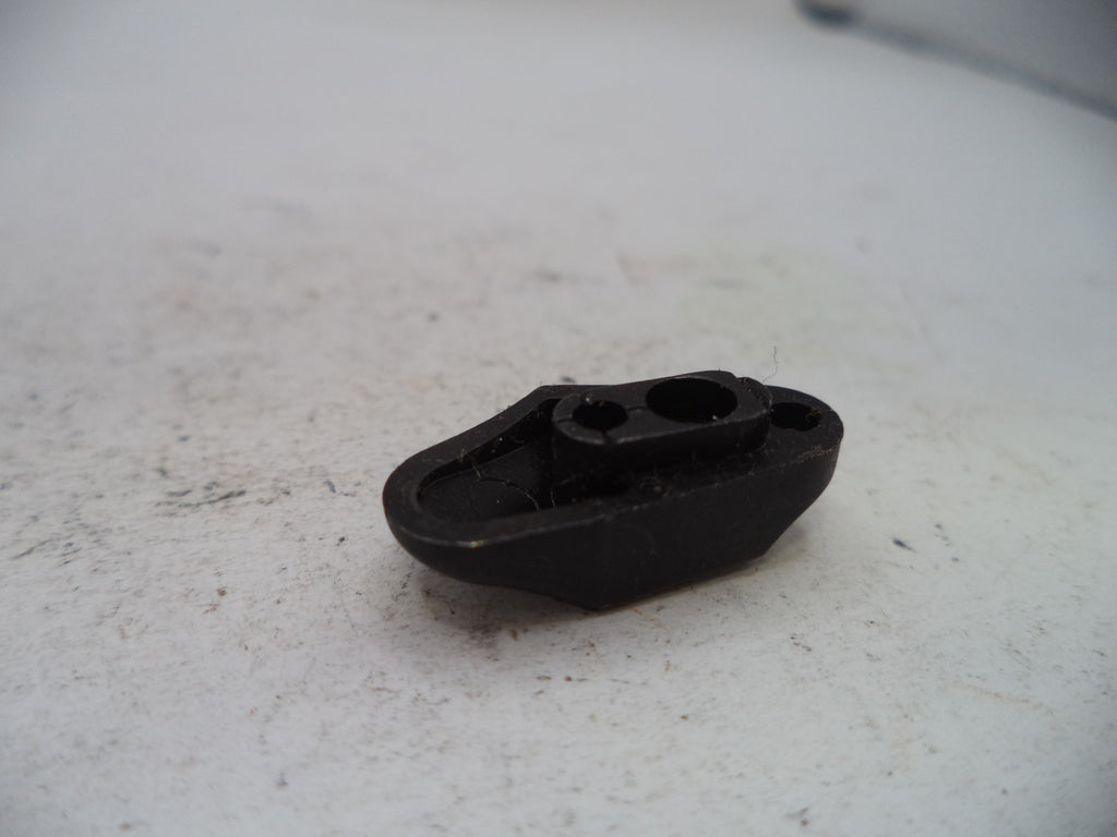 A small black plastic mechanical part with two circular openings, resting on a light gray textured surface.