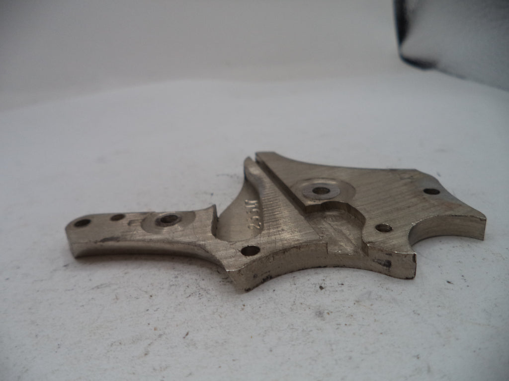 A used metal mechanical part, likely a bracket or guide, made of steel or aluminum with visible wear, scratches, and small mounting holes, resting on a white surface.