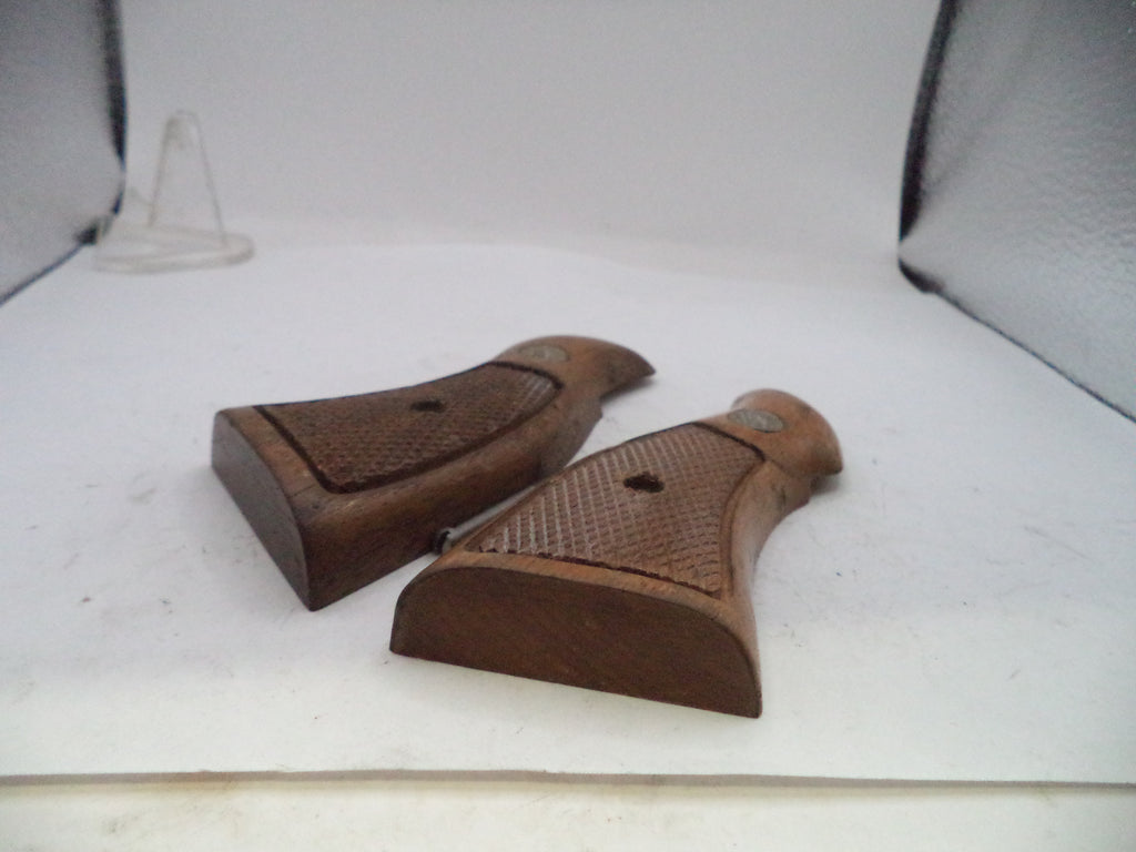 A pair of brown wooden pistol grip covers with textured checkered patterns and metal rivets, displayed on a white surface.