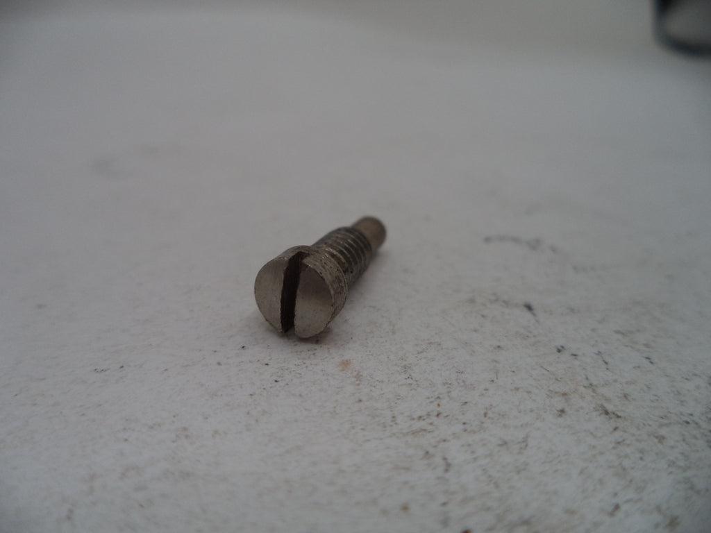 A small metal slotted screw with a threaded shaft, photographed on a light off-white textured surface.