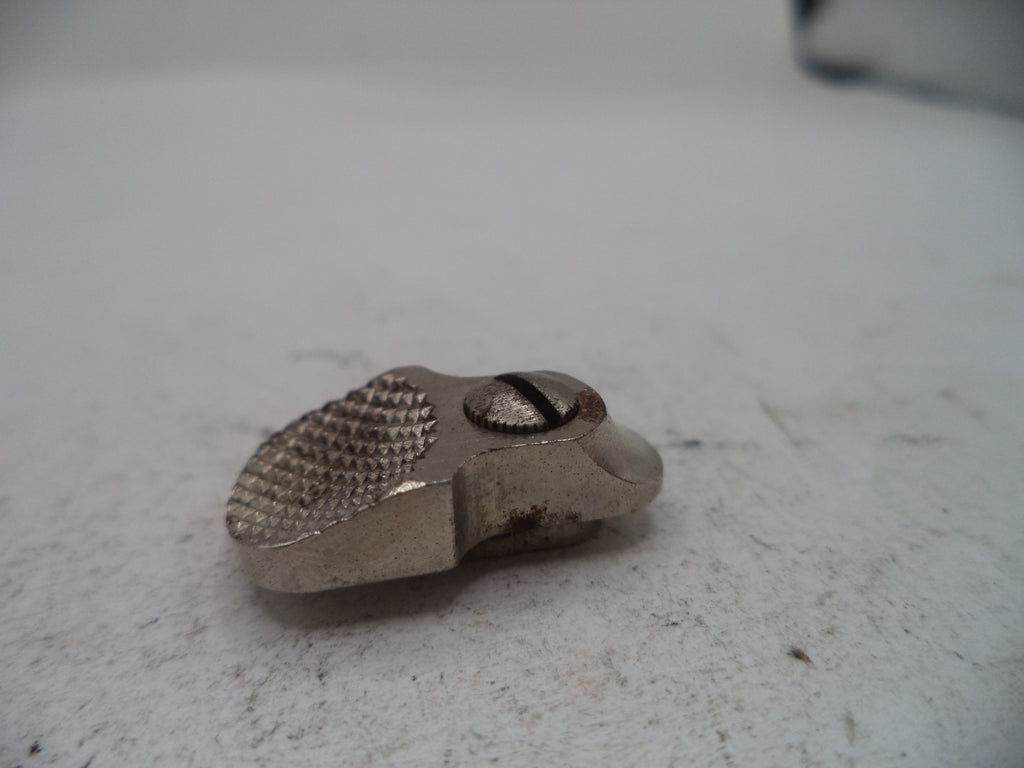 A small metallic silver tool or hardware piece with a textured surface and a central screw, resting on a light gray surface.