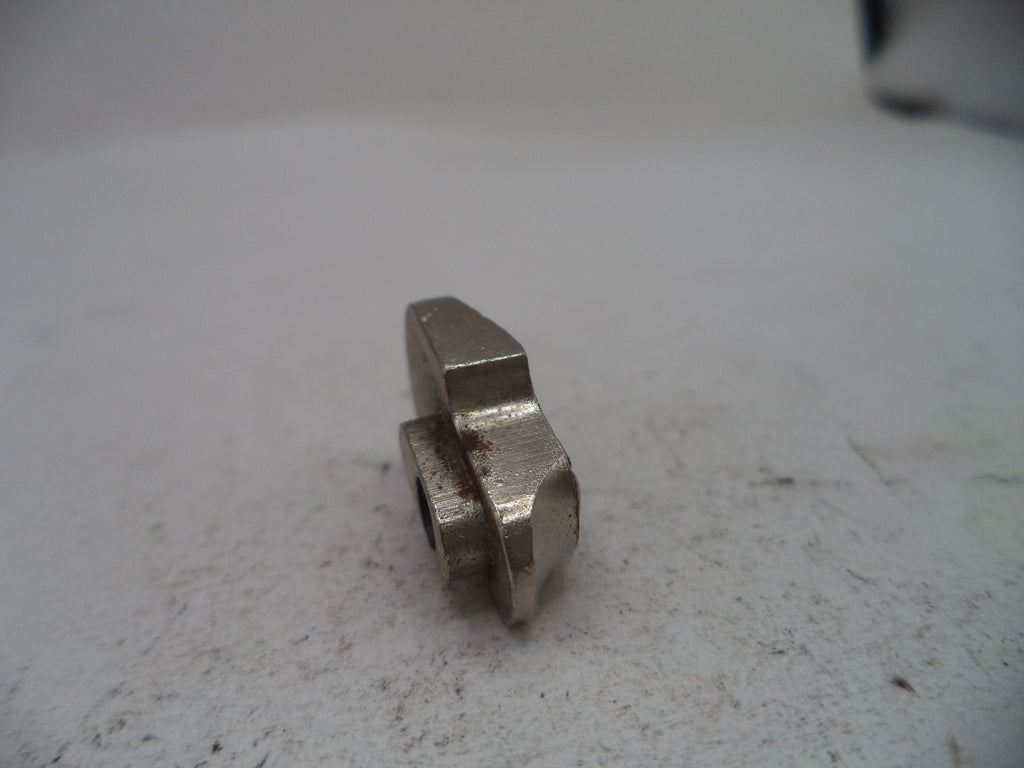 A small metallic silver hardware component, possibly a machined bolt head or spacer, resting on a textured off-white surface.
