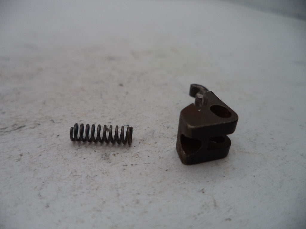 A small metal mechanical component and a coiled spring on a light gray surface.