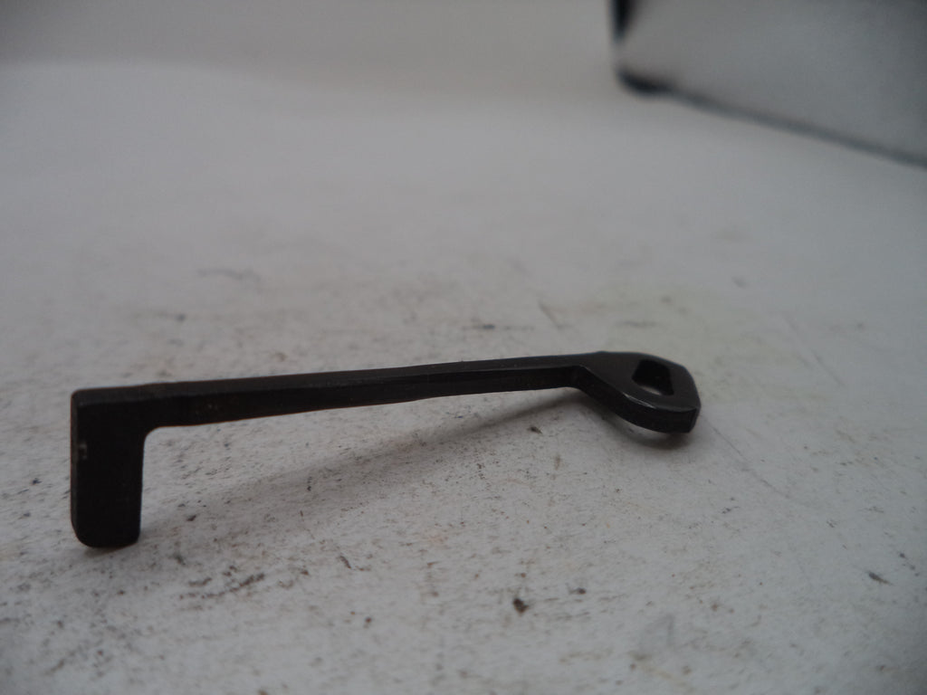 A small black metal hardware piece with a bent L-shaped end and a looped handle, photographed on a light gray surface.