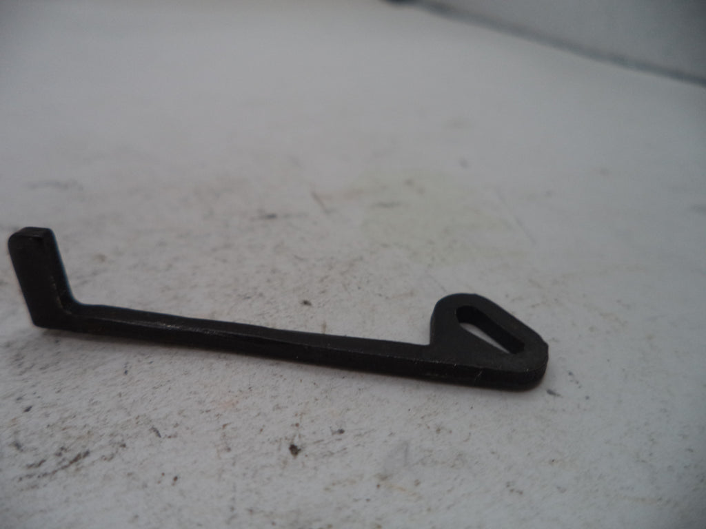 A small black metal bracket or hook with a triangular cutout at one end, photographed on a light gray textured surface.