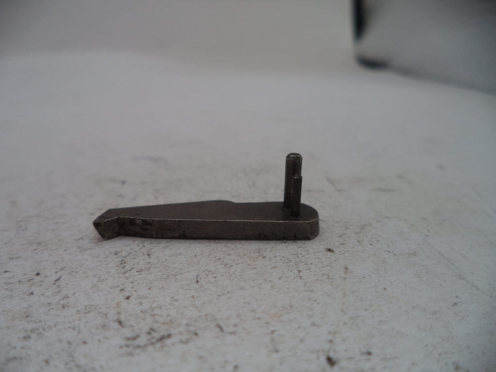 A small dark metal hardware component with a flat rectangular plate and a short vertical pin, photographed on a light textured surface.