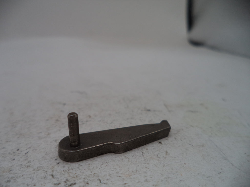 A small dark metal hardware piece with a flat triangular blade and a short vertical pin, photographed on a light gray textured surface.