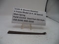 A used metal main spring part for a Smith & Wesson revolver, displayed on a small clear plastic stand with a white paper label showing the part number and description.