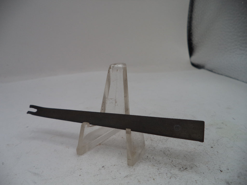 A flat metal tool with a forked tip, displayed horizontally on a clear plastic stand against a plain light background.