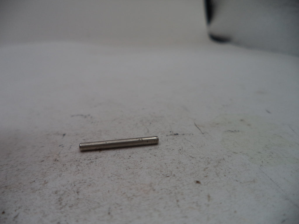 A small metallic cylindrical pin or rod lying on a dirty off-white surface.