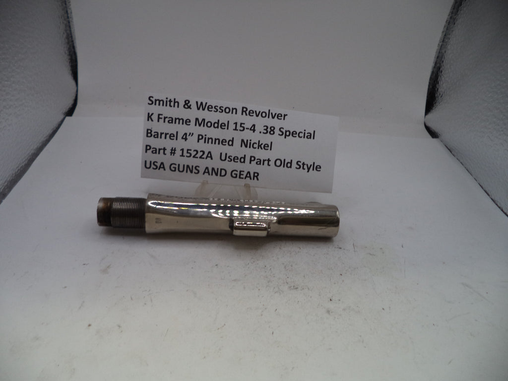 A used metal barrel component for a Smith & Wesson revolver, displayed on a white surface with a handwritten label card behind it.