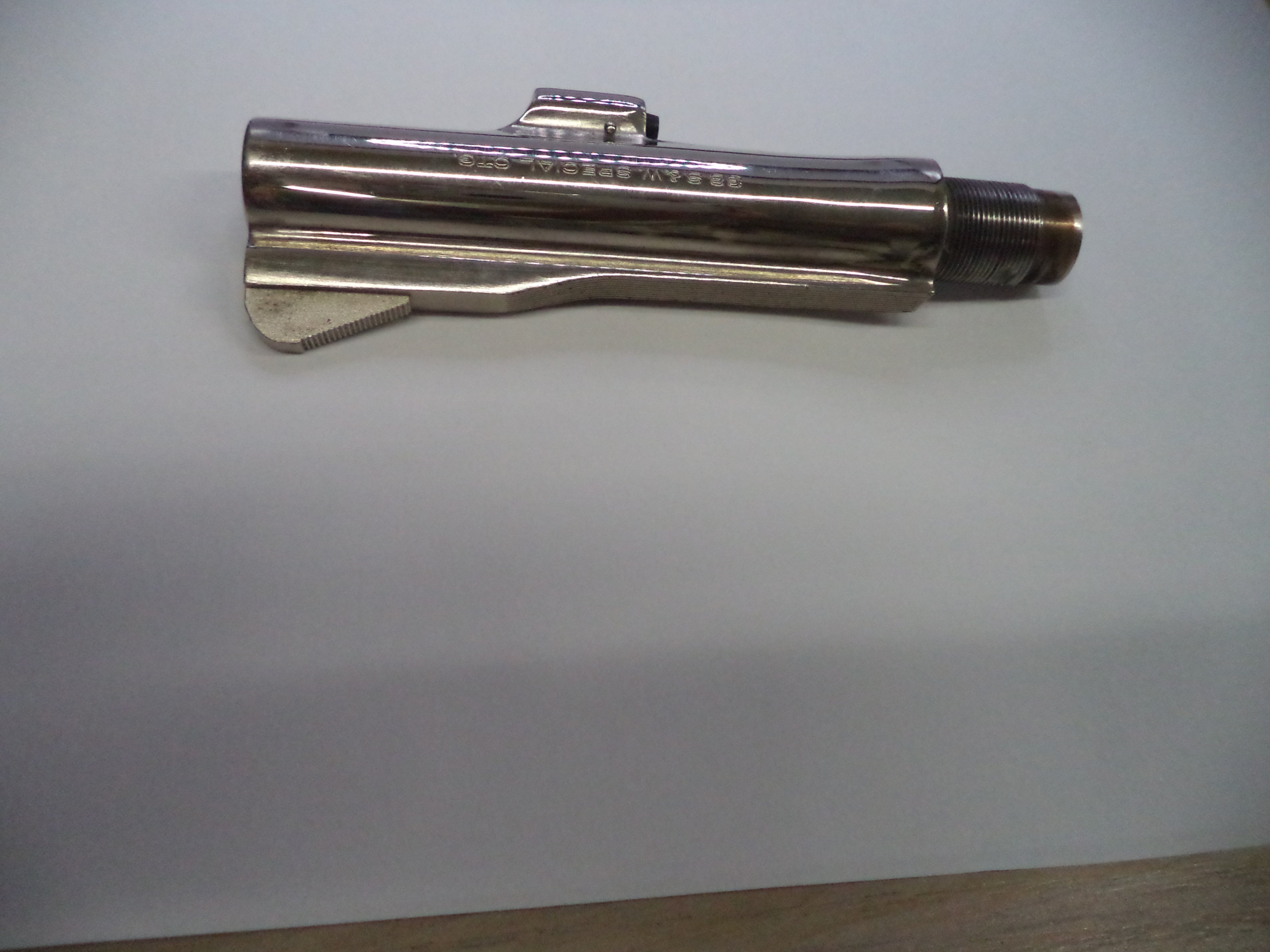 A metallic silver cylindrical tool or hardware piece with engraved text, photographed on a plain light background.