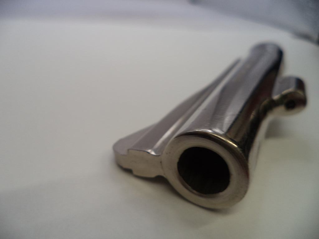A close-up shot of a polished metallic gun barrel tip or muzzle component on a plain light background.
