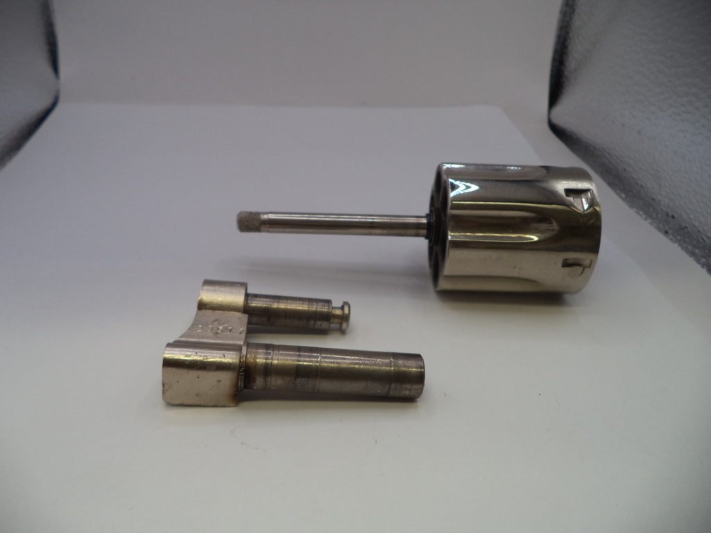 A set of metallic mechanical parts, including a cylindrical metal sleeve with a long shaft and two smaller metal cylindrical components, displayed on a white surface.