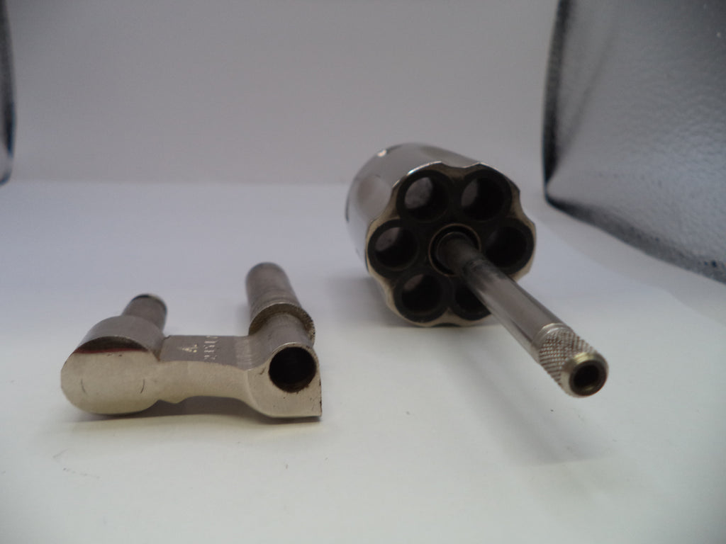 A pair of vintage metallic revolver cylinder wrenches on a white surface, one flat and one angled to show the six-spoke socket and knurled barrel shank.