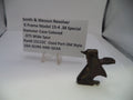 A used metal hammer case part for a Smith & Wesson revolver, displayed next to a white label card on a clear stand against a white background.