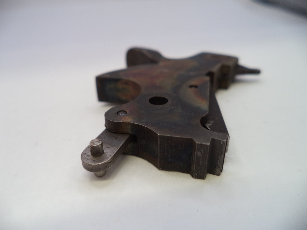 A dark, weathered metal mechanical part with a rusted and oxidized finish, resting on a plain white surface.