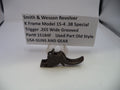 A small dark metal Smith & Wesson revolver trigger part displayed on a clear stand in front of a white label card with printed product details.