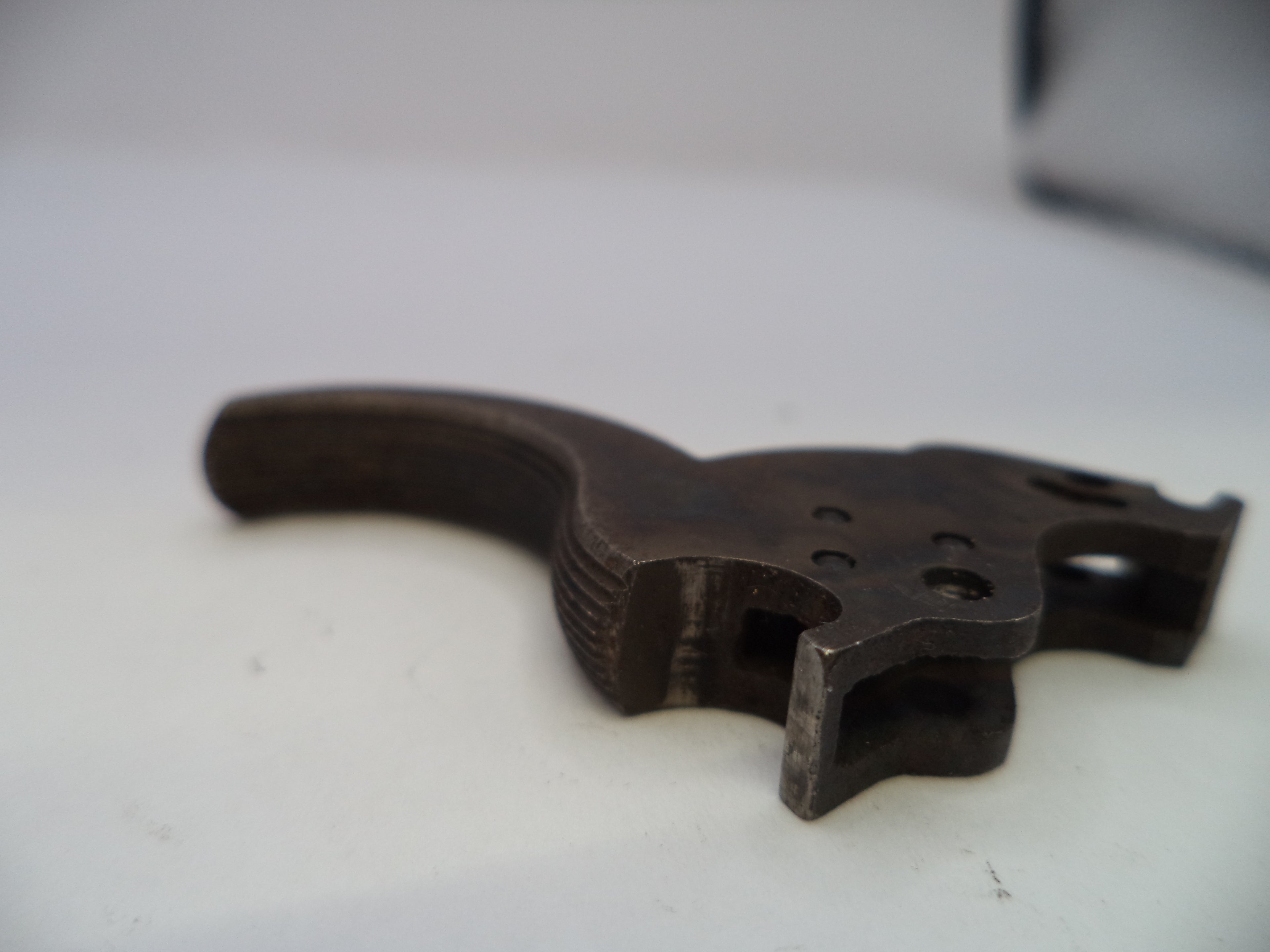 A dark metal firearm trigger assembly, likely a receiver trigger or pistol trigger component, shown on a plain white surface.