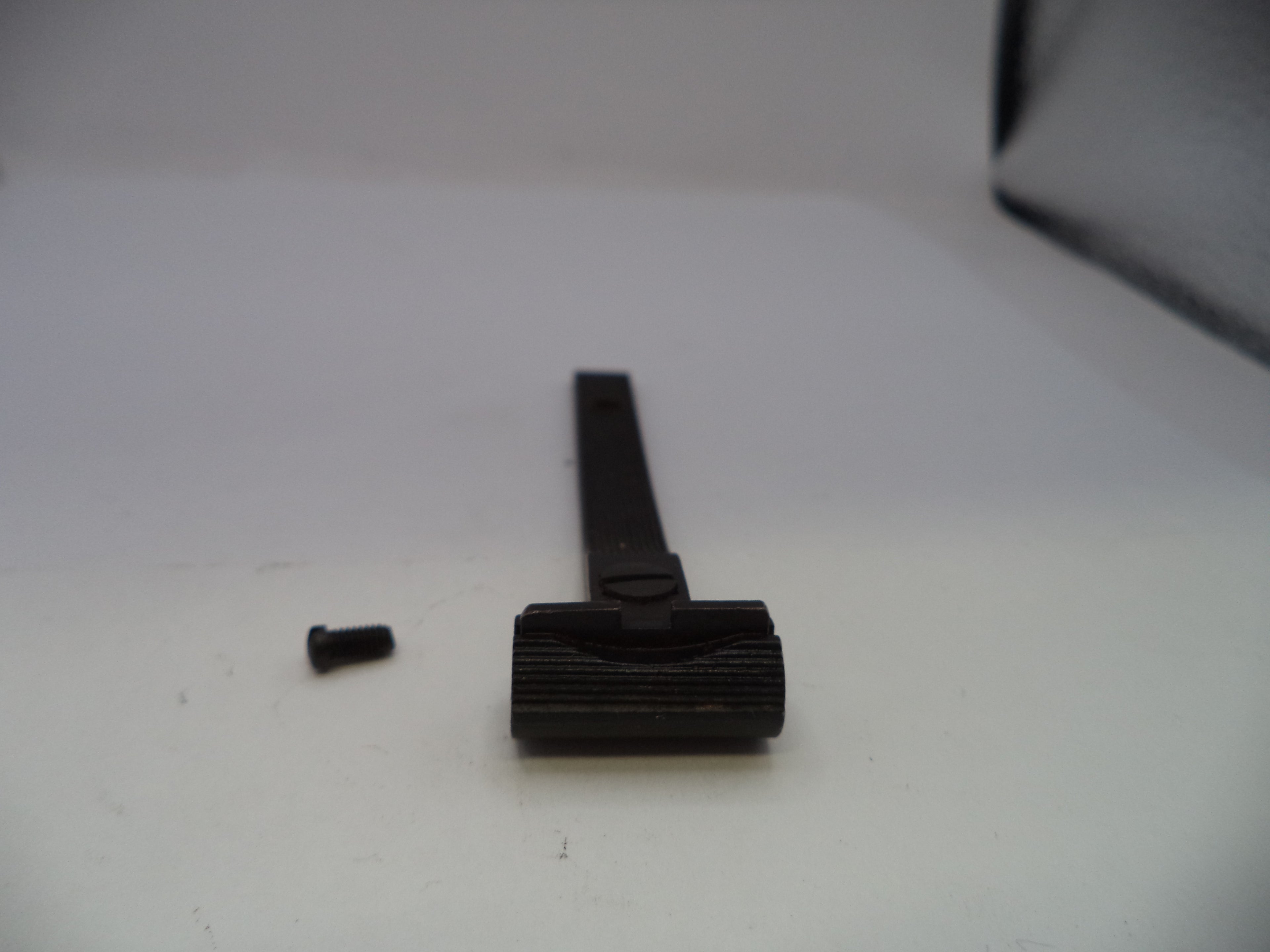 A black plastic or metal razor handle with a textured grip and a small detached screw, photographed on a plain light background.