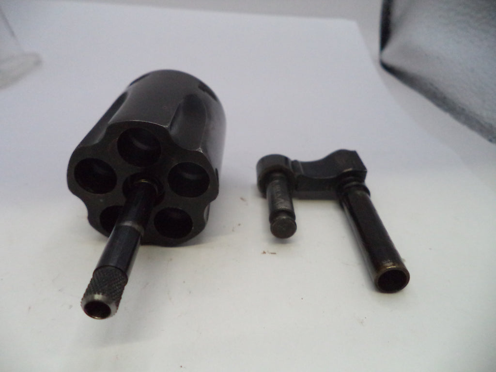 A black metal revolver cylinder and a black metal barrel sleeve or adapter, shown as a set on a plain white surface.