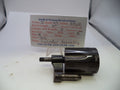 A used metal cylinder assembly for a Smith & Wesson revolver, displayed on a white surface with a paper parts card in the background.