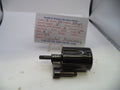 A black metal revolver cylinder assembly part, photographed on a white surface with a handwritten parts label card behind it reading Smith & Wesson Revolver Parts.