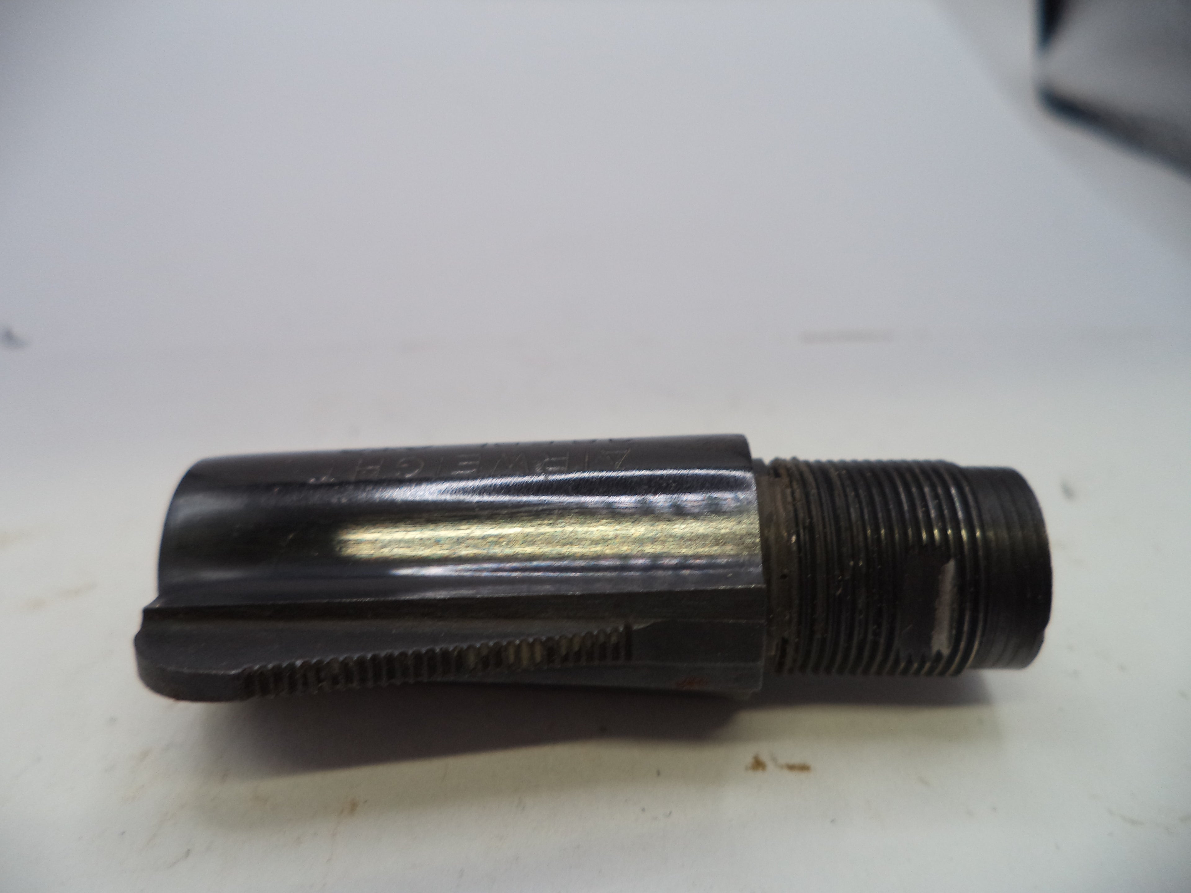 A used black metal threaded component, likely a mechanical adapter or tool shank, photographed on a white surface.
